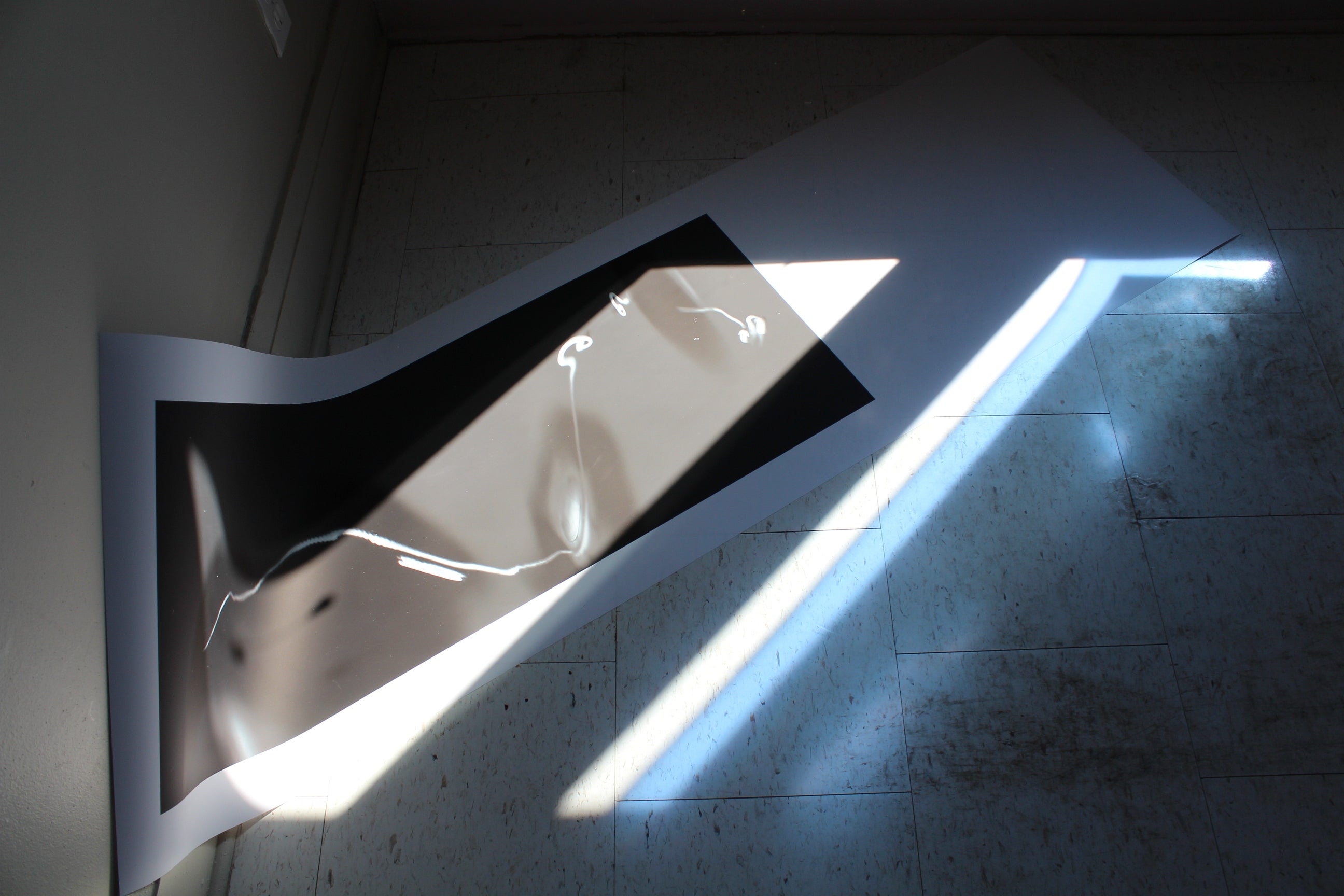 Sunlight shines on black and white abstract picture lying on the floor