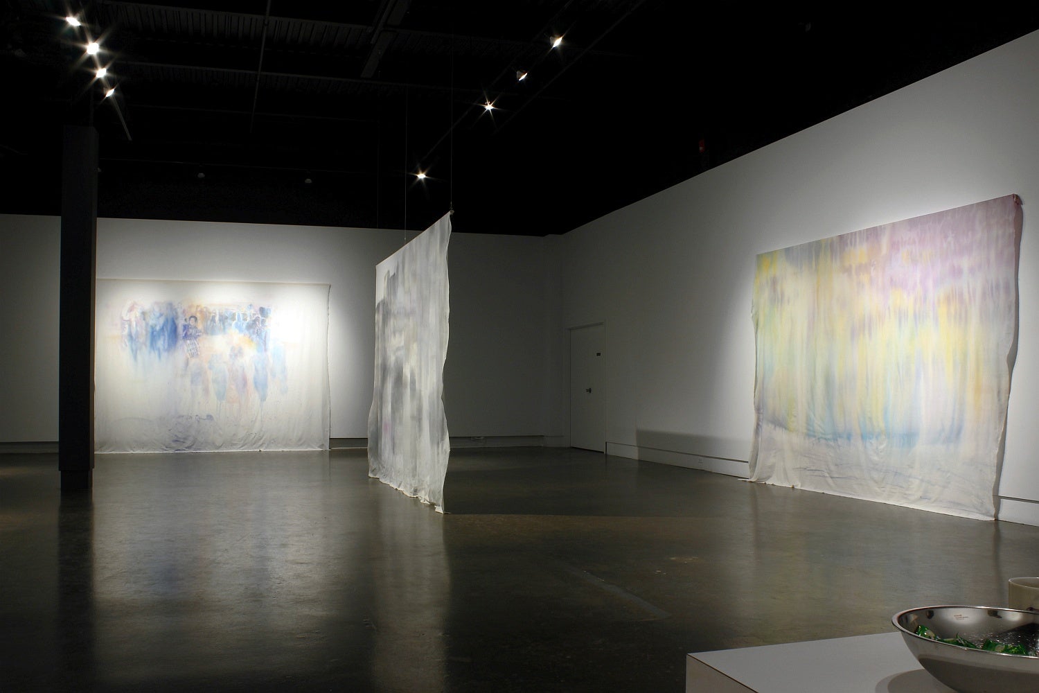 Art gallery with large rectangular hanging banners with ink wash paintings of cityscapes. 