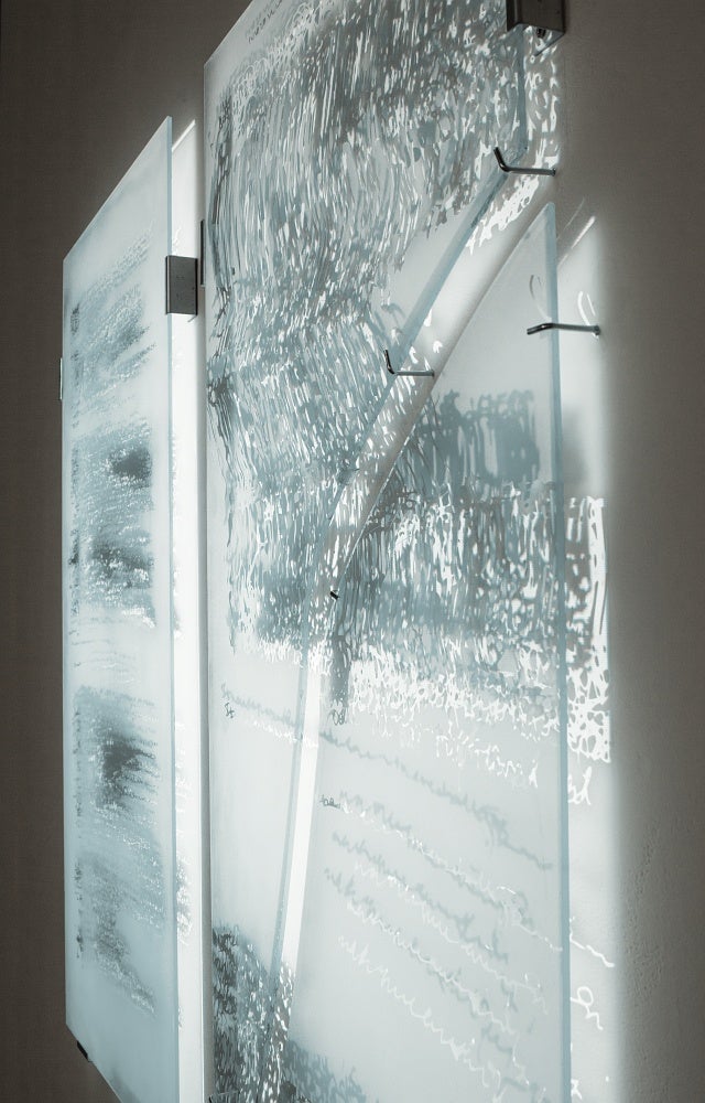 Light is projected onto glass panels, sandblasted with a pattern from medical imaging, which are hung away from the wall causing the light to be shine through.