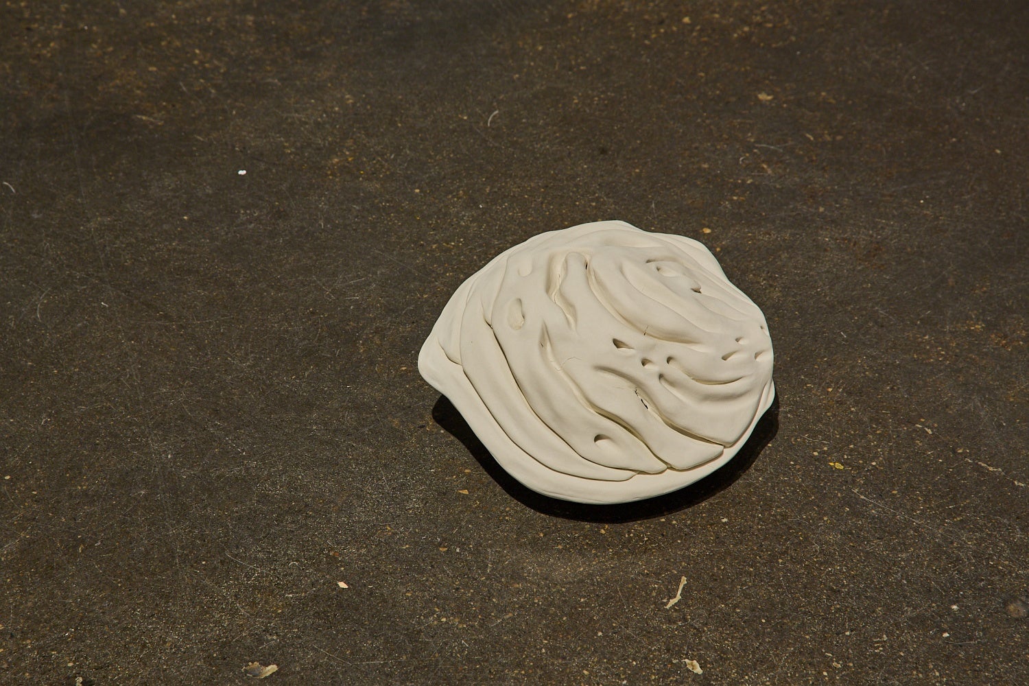 A large off-white porcelain peach pit rests on the floor.