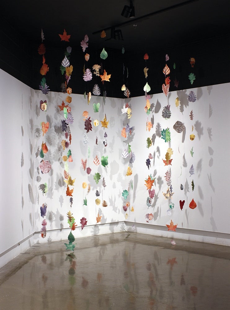 Art installation of multiple strings, hung from the ceiling, of multicolour, leaf shaped, lino prints 