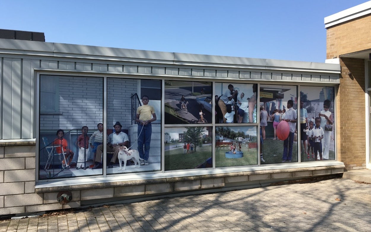 Large scale photographic installation of family on photos from the 1960s installed on the windows of a building