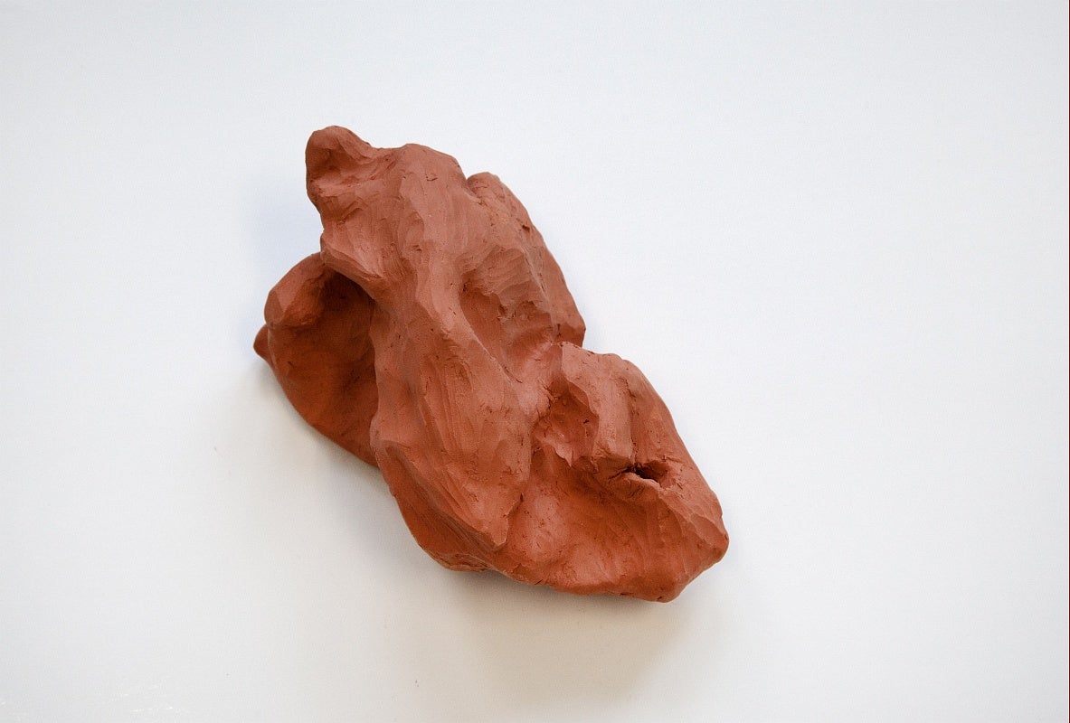 Sculpture of red clay molded into a rock-like shape.