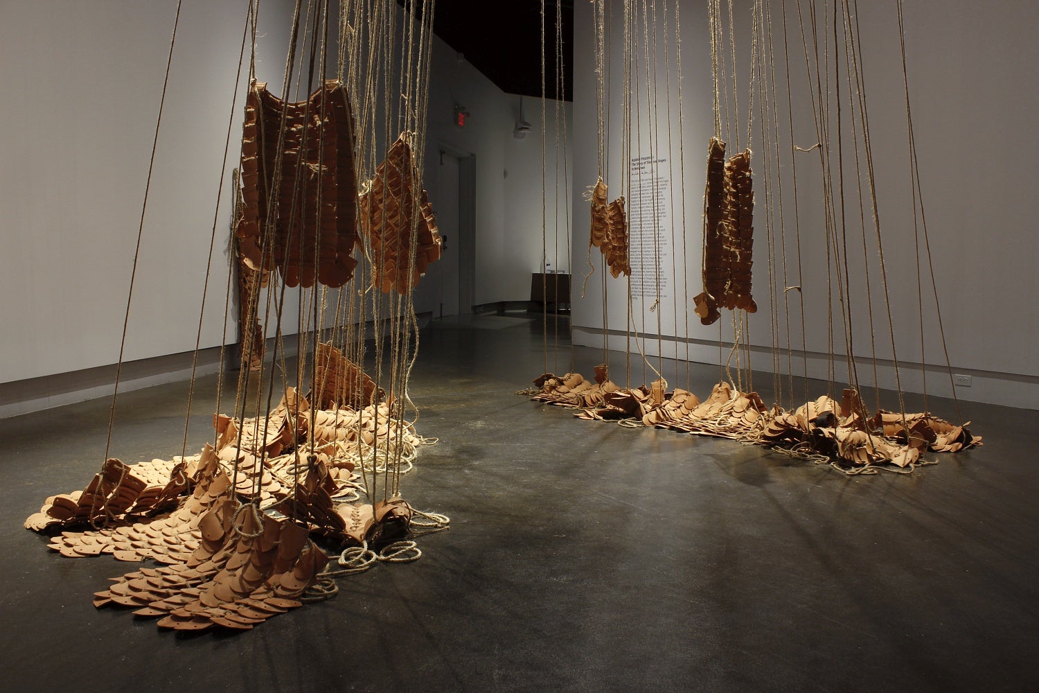 Multiple rounded clay tiles bound together using jute hang from the ceiling and piled on the floor.