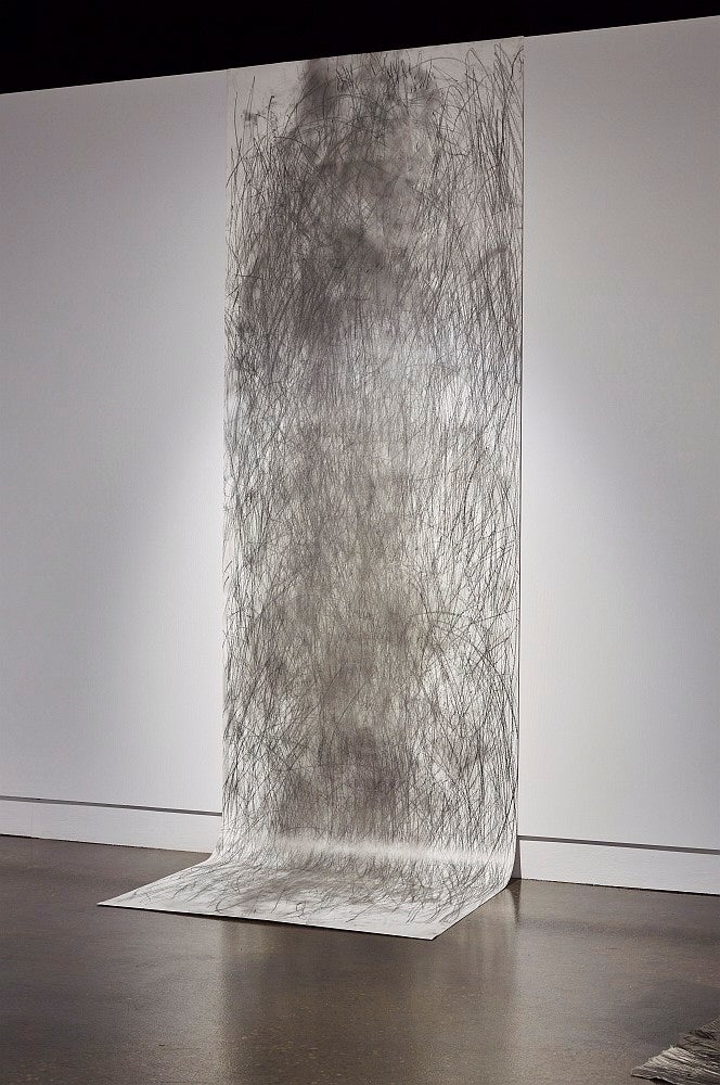 A large hanging drawing of graphite strokes drapes onto the floor.