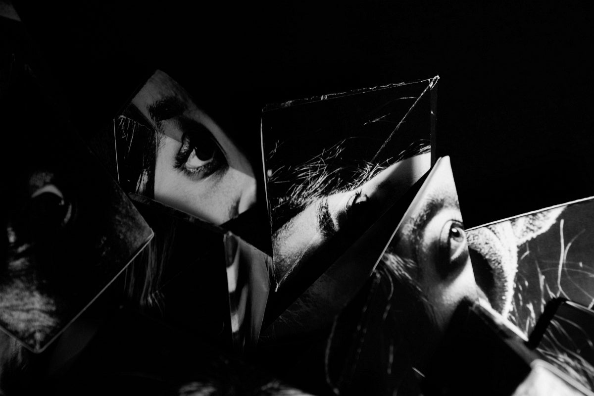 Artwork of a pile of pyramid shapes made from cut and folded black and white portrait photographs.