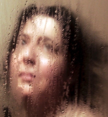 Colour photograph showing person looking through condensation covered glass