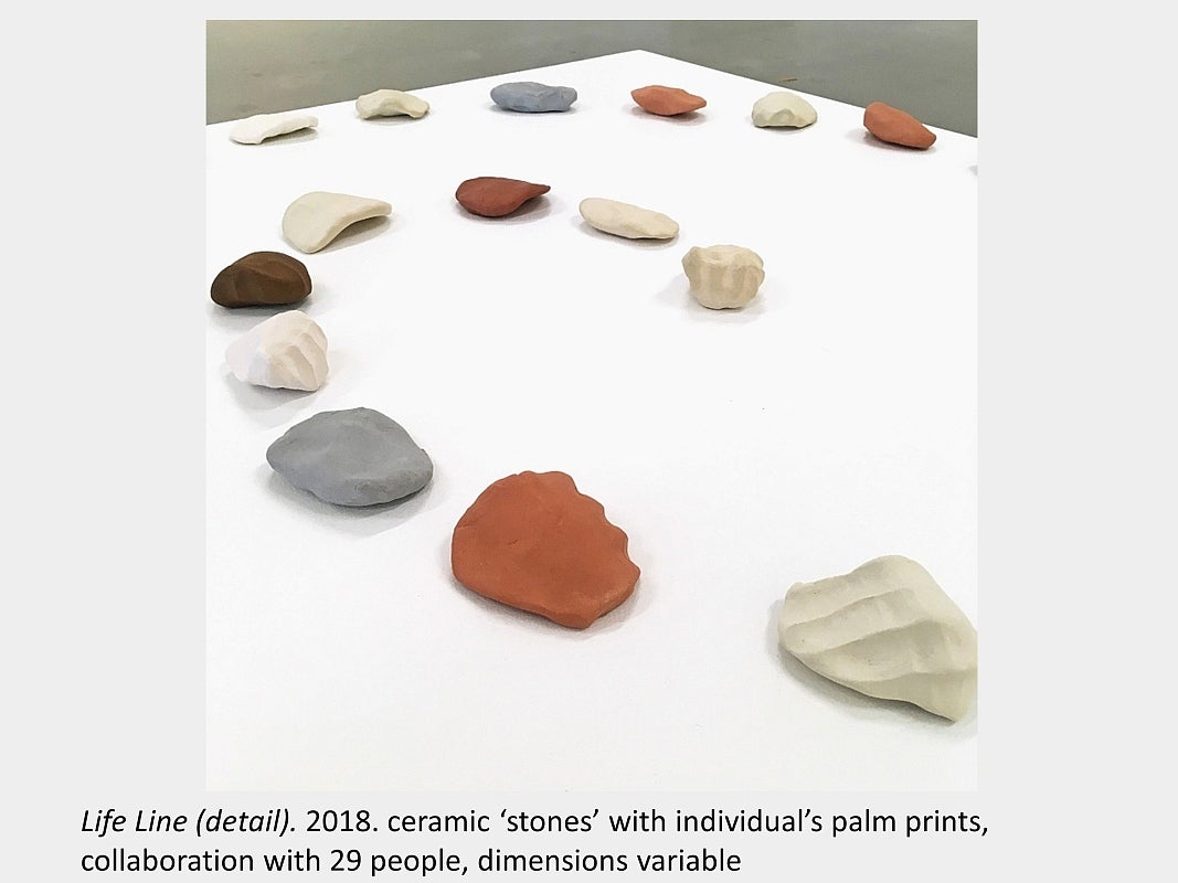 Artwork by Sara Pearson - Life Line (detail). 2018. ceramic ‘stones’ with individual’s palm prints, collaboration with 29 people
