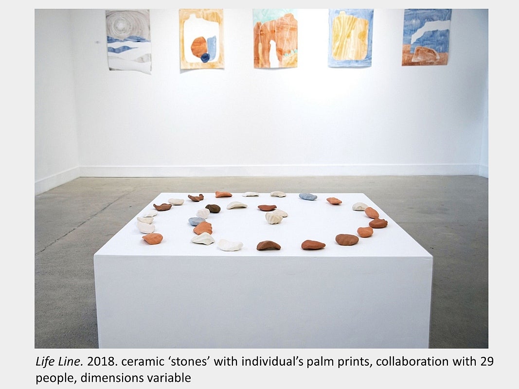 Artwork by Sara Pearson - Life Line. 2018. ceramic ‘stones’ with individual’s palm prints, collaboration with 29 people,