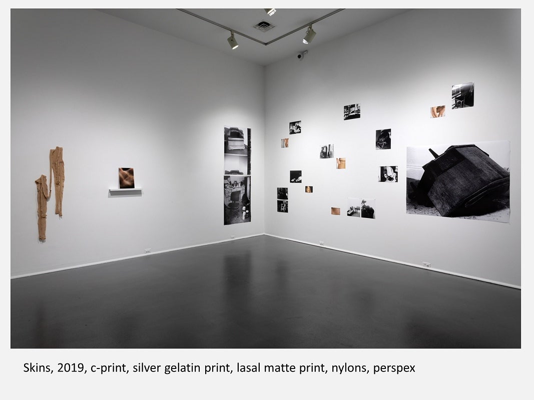 Gallery with photographs, most black and white, and nylon stockings, hung in random pattern on walls