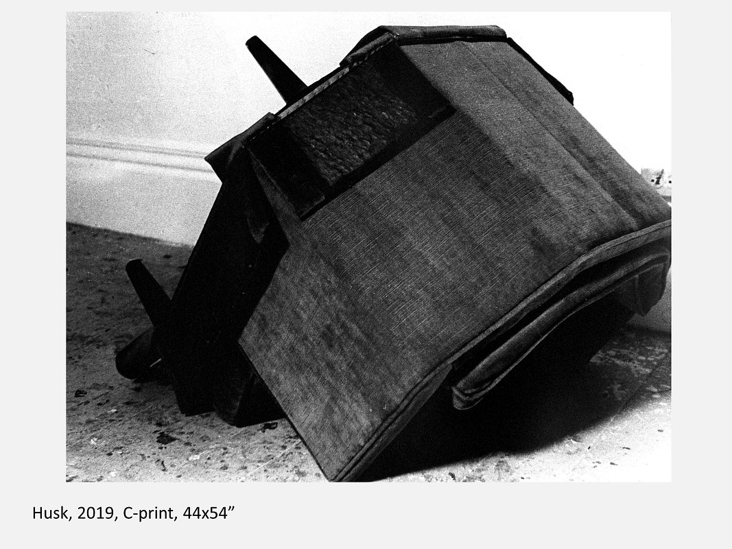 Black and white image of an armchair upside down on the floor