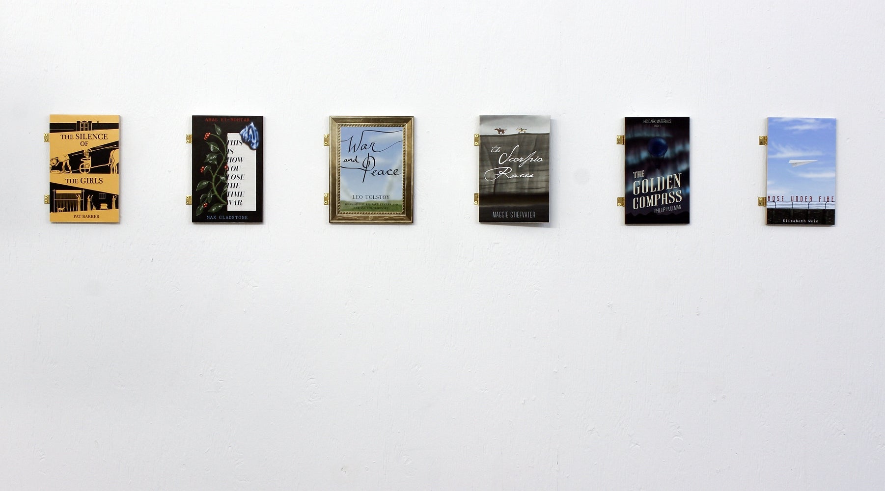 Art installation of 6 book covers attached to the wall with hinges.