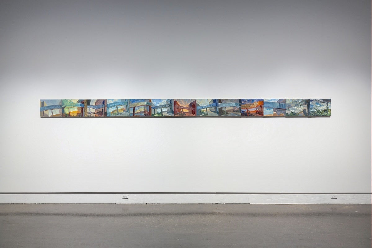 Thirteen small, colourful paintings and hung edge to edge in a line.  The paintings show views of a pedestrian overpass between building. 