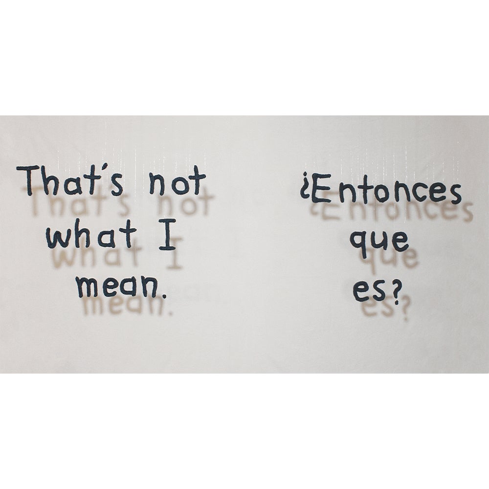 Hanging alphabetic letters cast a shadow on the wall behind.  Text reads "That's not what I mean. ¿Entonces que es? "