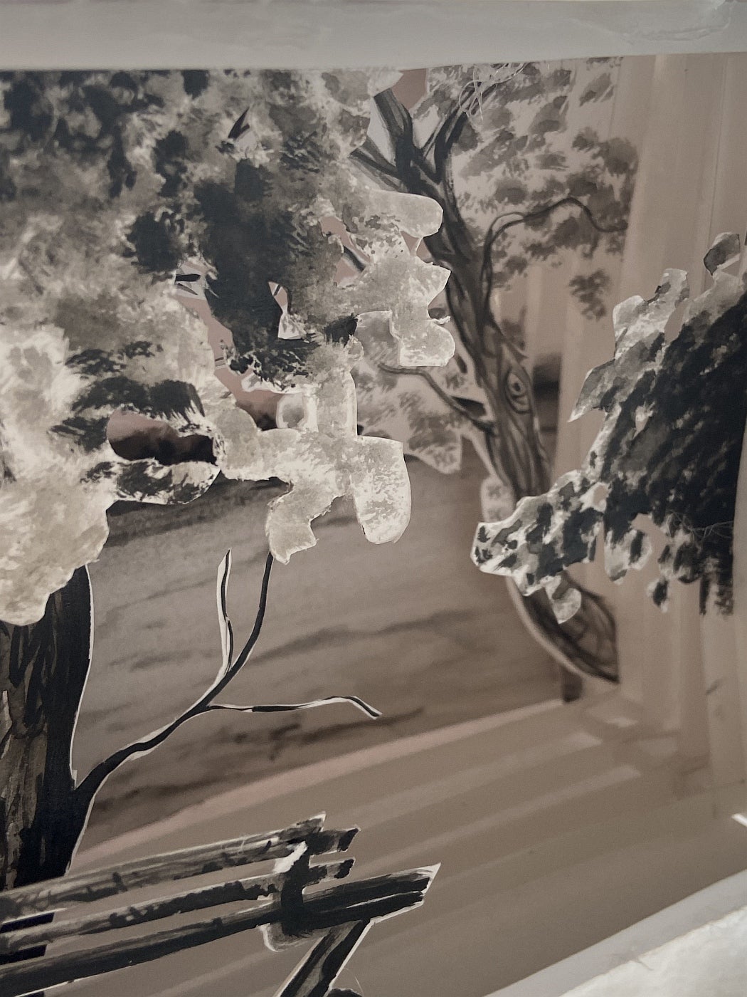 Shadow box made of paper layers showing a landscape with trees and a park bench in front.