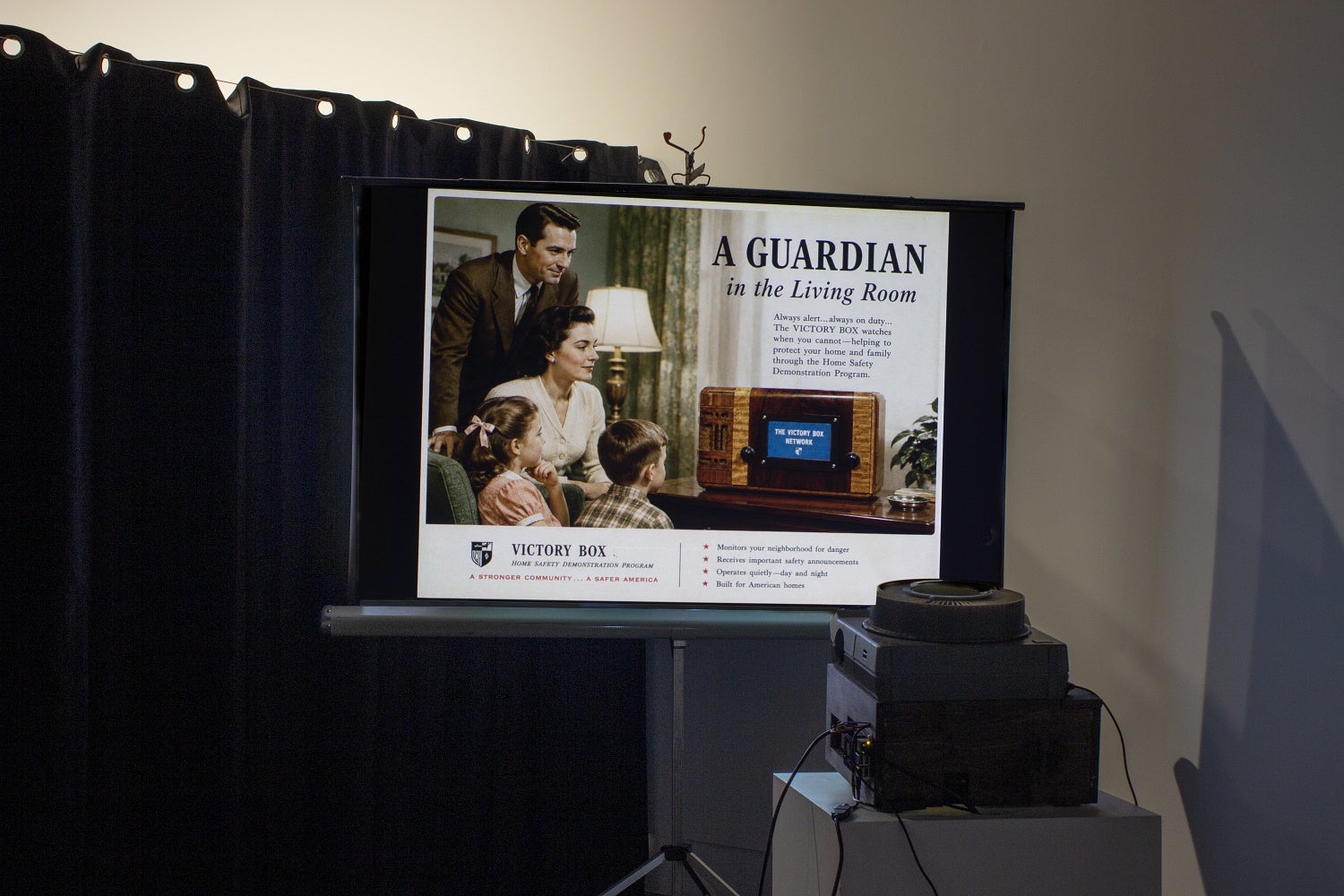 A projection screen in front of a 35mm slide projector show an AI generated 1950s style advertisement for Victory Box.