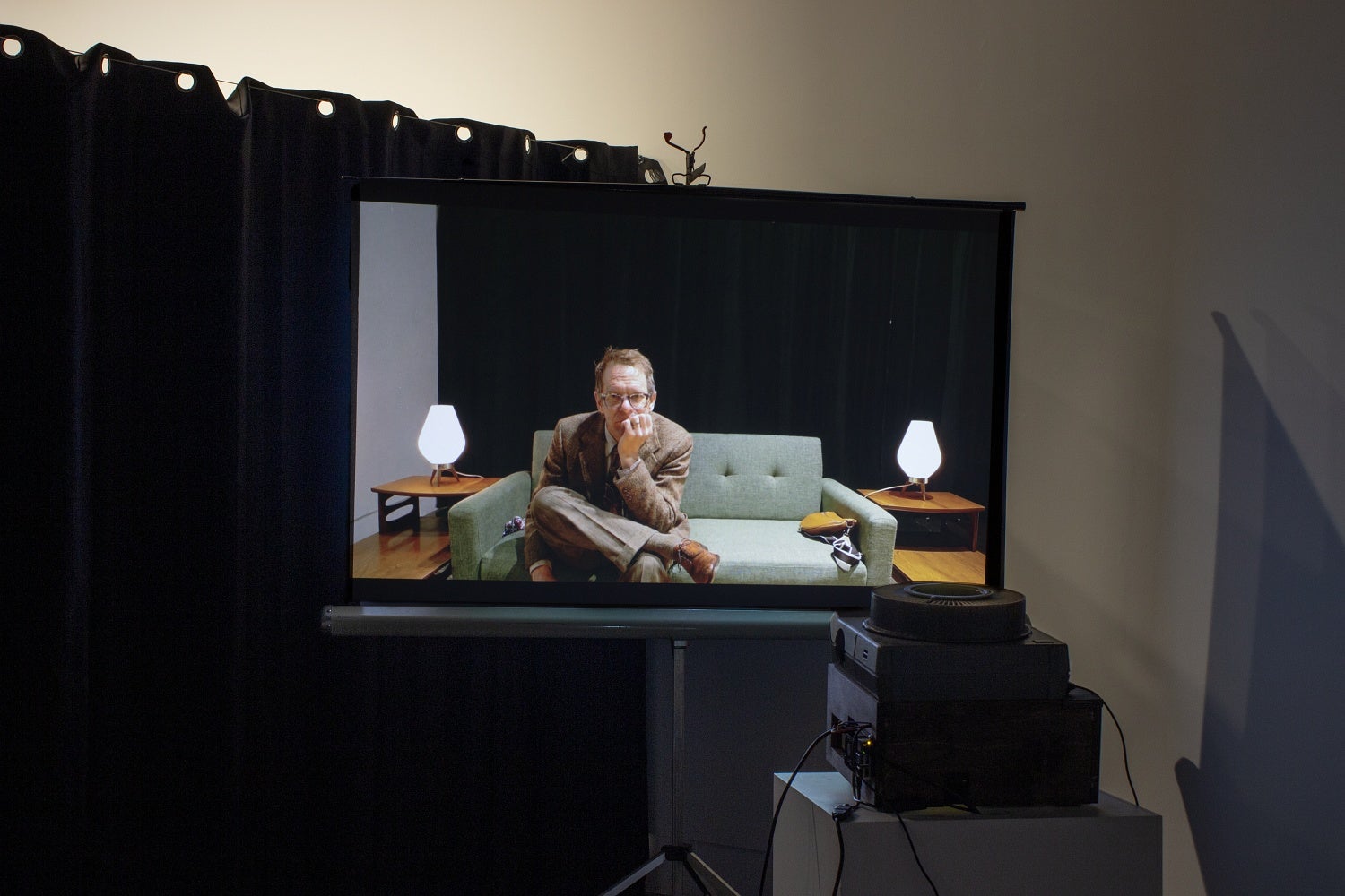 A projection of an AI manipulated photo showing a man in vintage clothing in a mid-century decor living room.