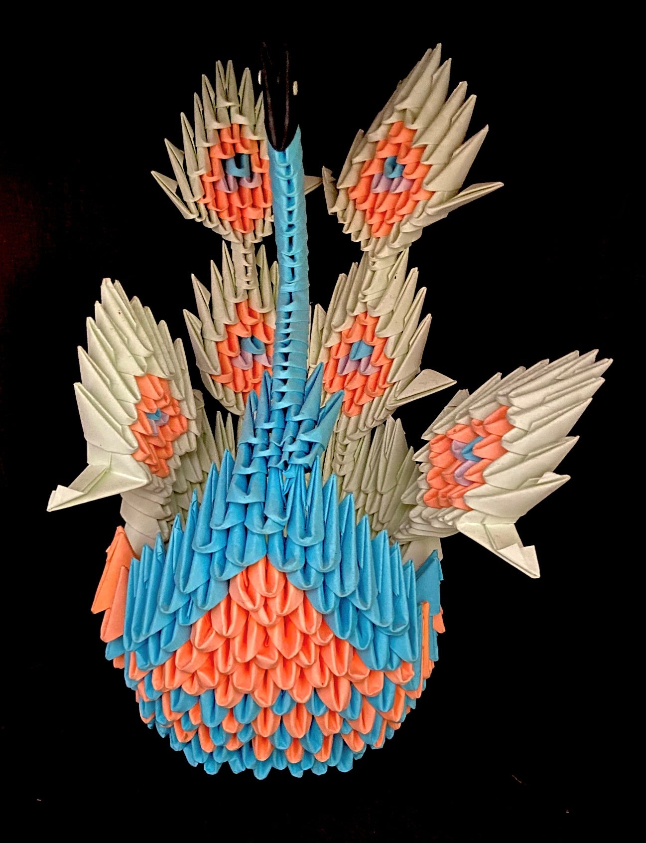 Stylized peacock made in origami.  Beige, orange, blue and pink.