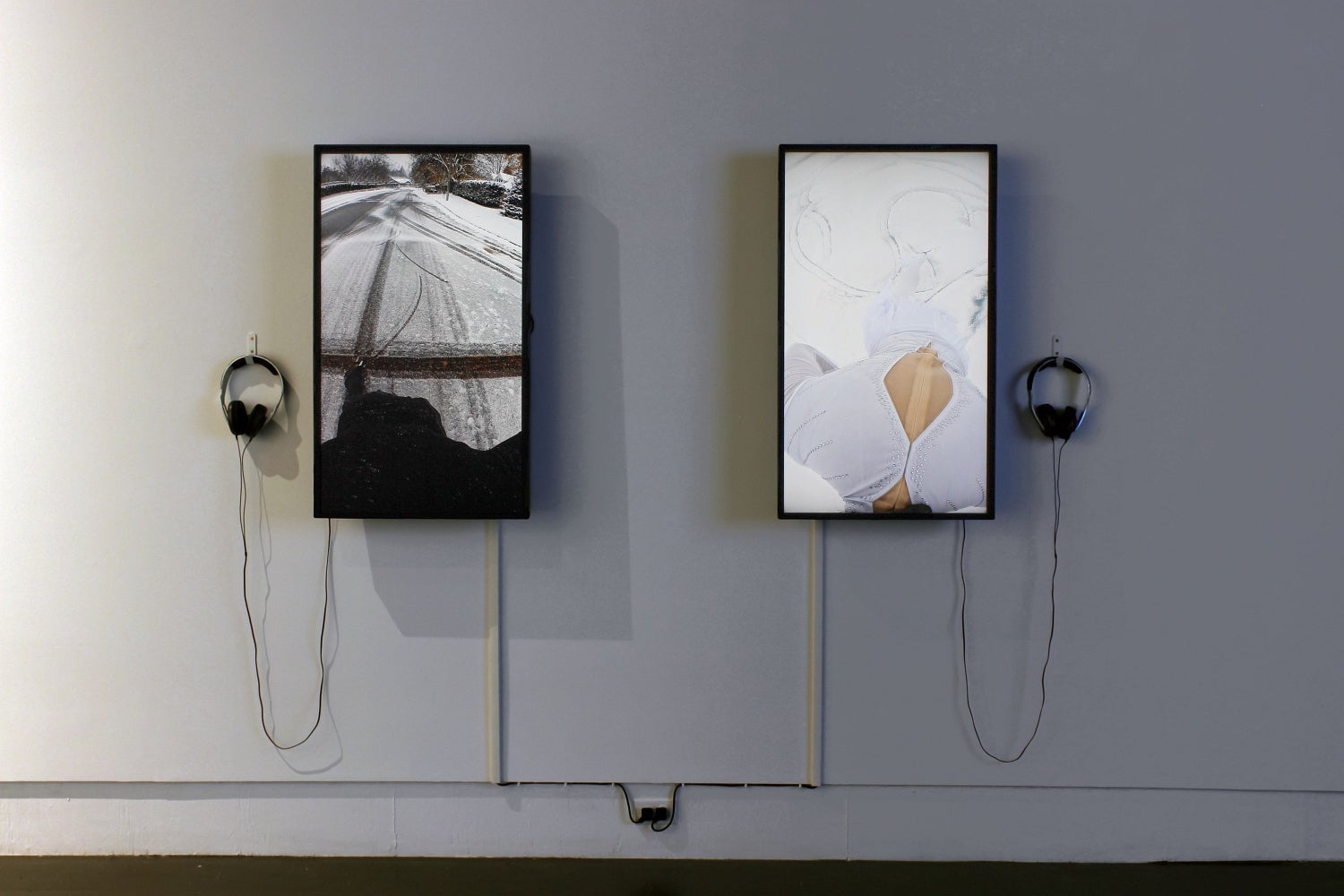 Two screens, hung vertically, show the marks left in the snow behind as a person skates.