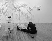 Sherri Hay seated on the floor, facing away from the camera.