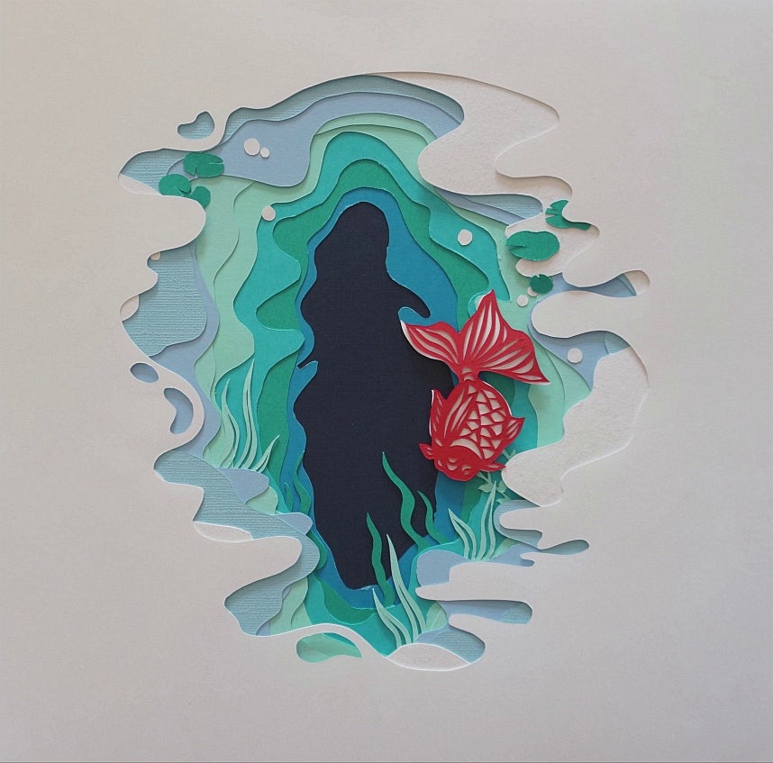 Paper cut-out artwork, white paper cut to reveal pages in shades of blue and green like water, orange carp swims.