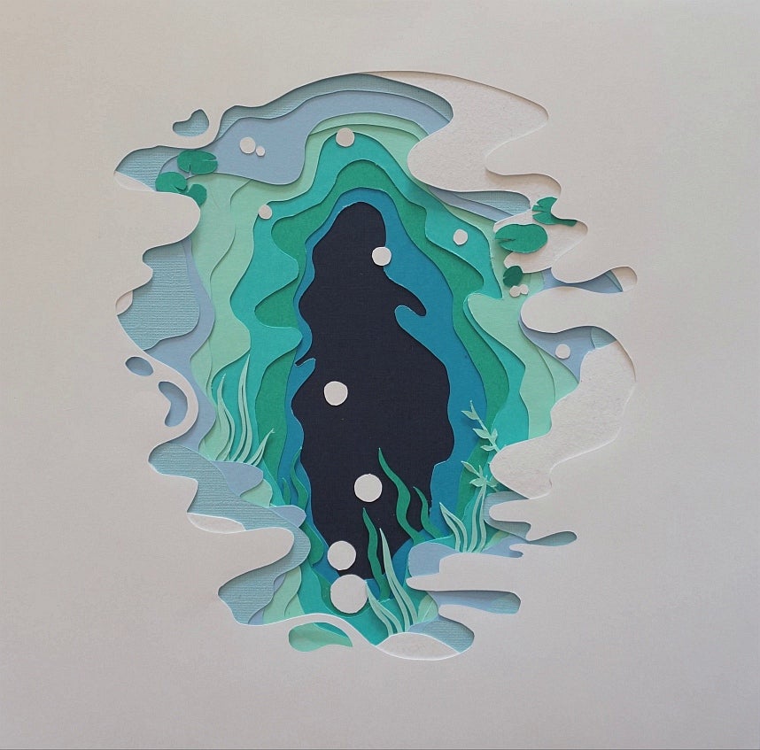Paper cut-out artwork, white paper cut to reveal pages in shades of blue and green like water, small white circle like bubbles.