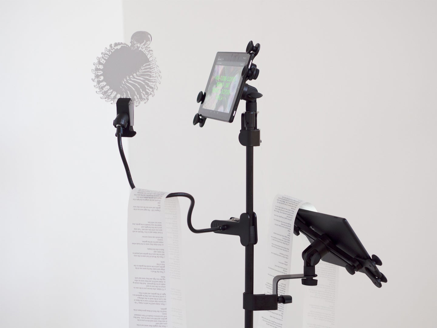 Artwork of multiple digital tablets secured to a stand with a scroll of paper with computer generated poetry. 