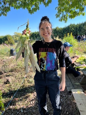 University student holds up white corn they braided together