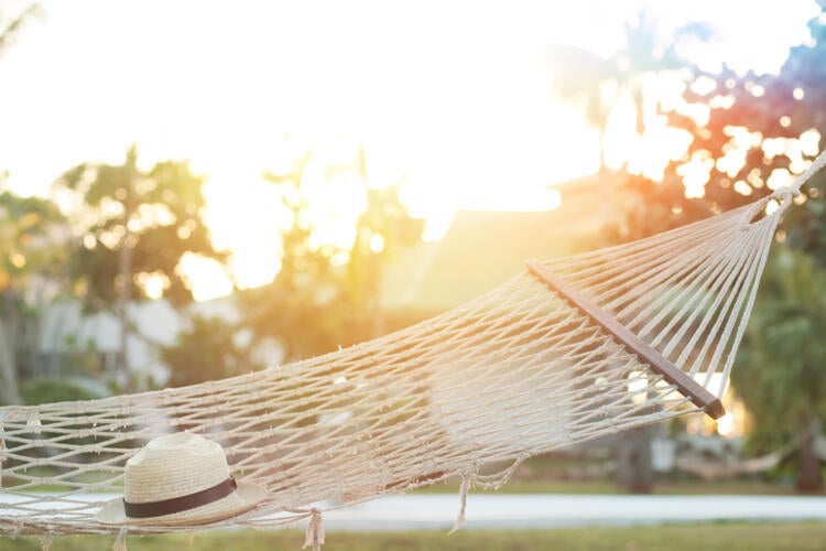 Image of hat on hammock, with sunset in back drop.