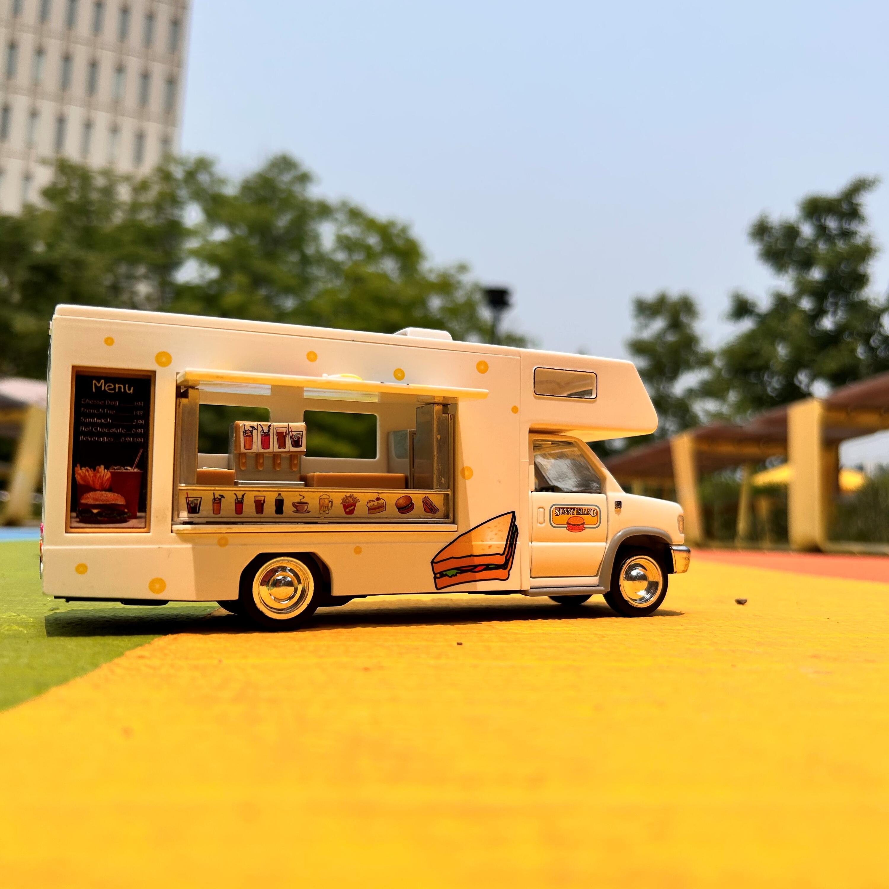 Toy food truck on a yellow pavement with trees in the background