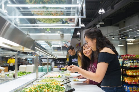 Two women serving themselves at a salad bar