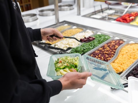 student taking out food into a green container 