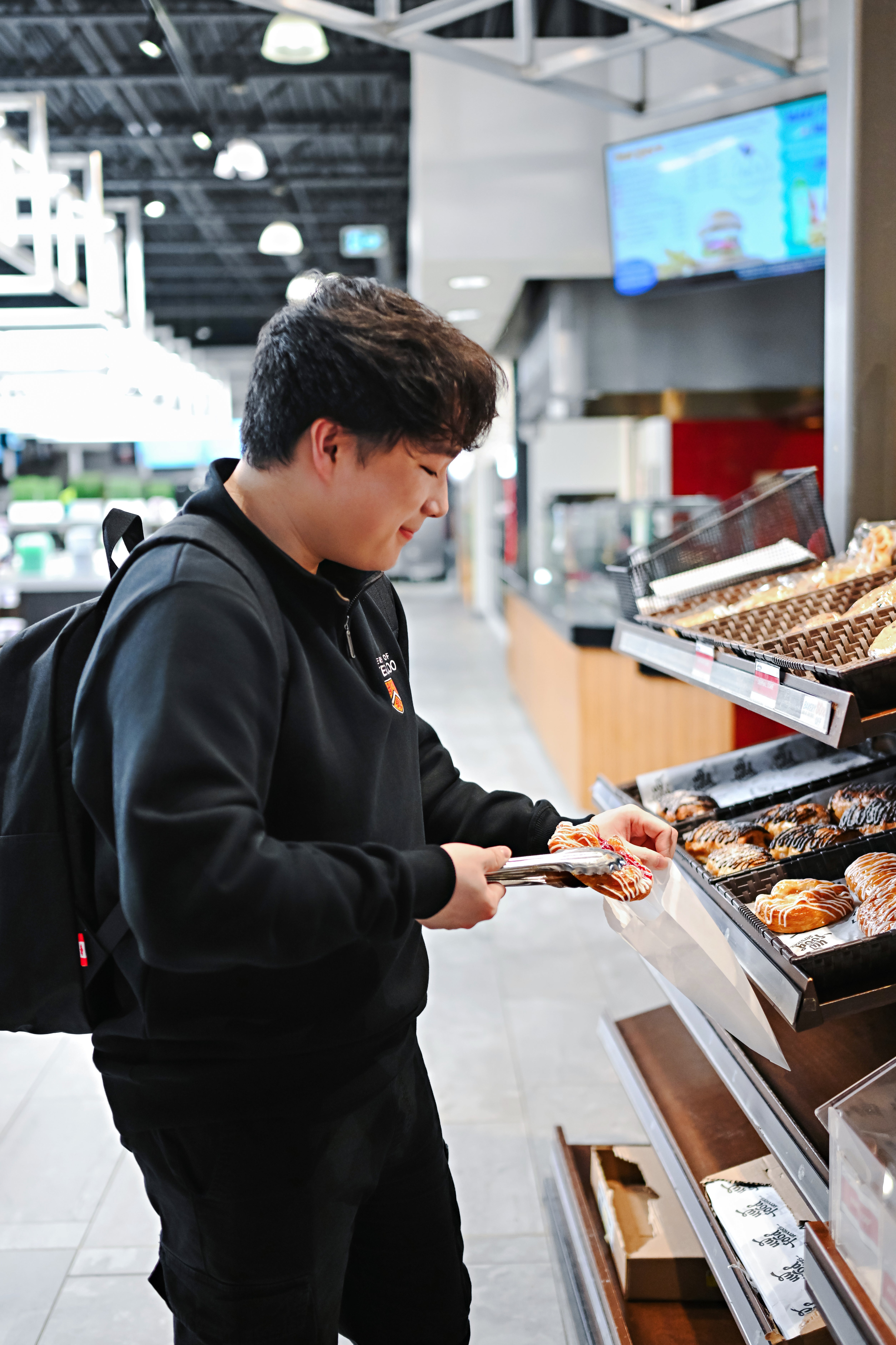 Student selecting a pastry from a campus bakery display.