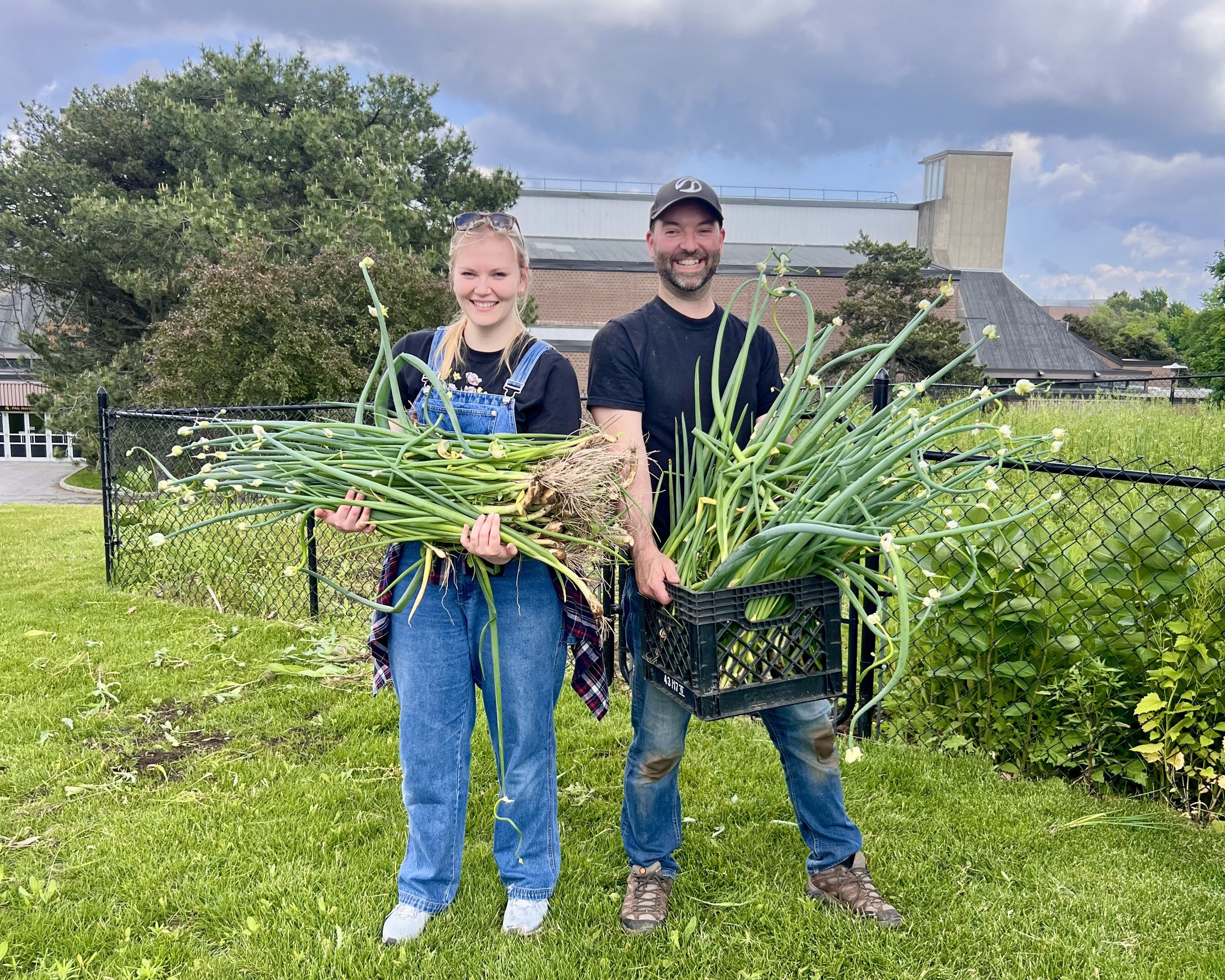 Food Service staff members holding up crates of onions outside the UC garden