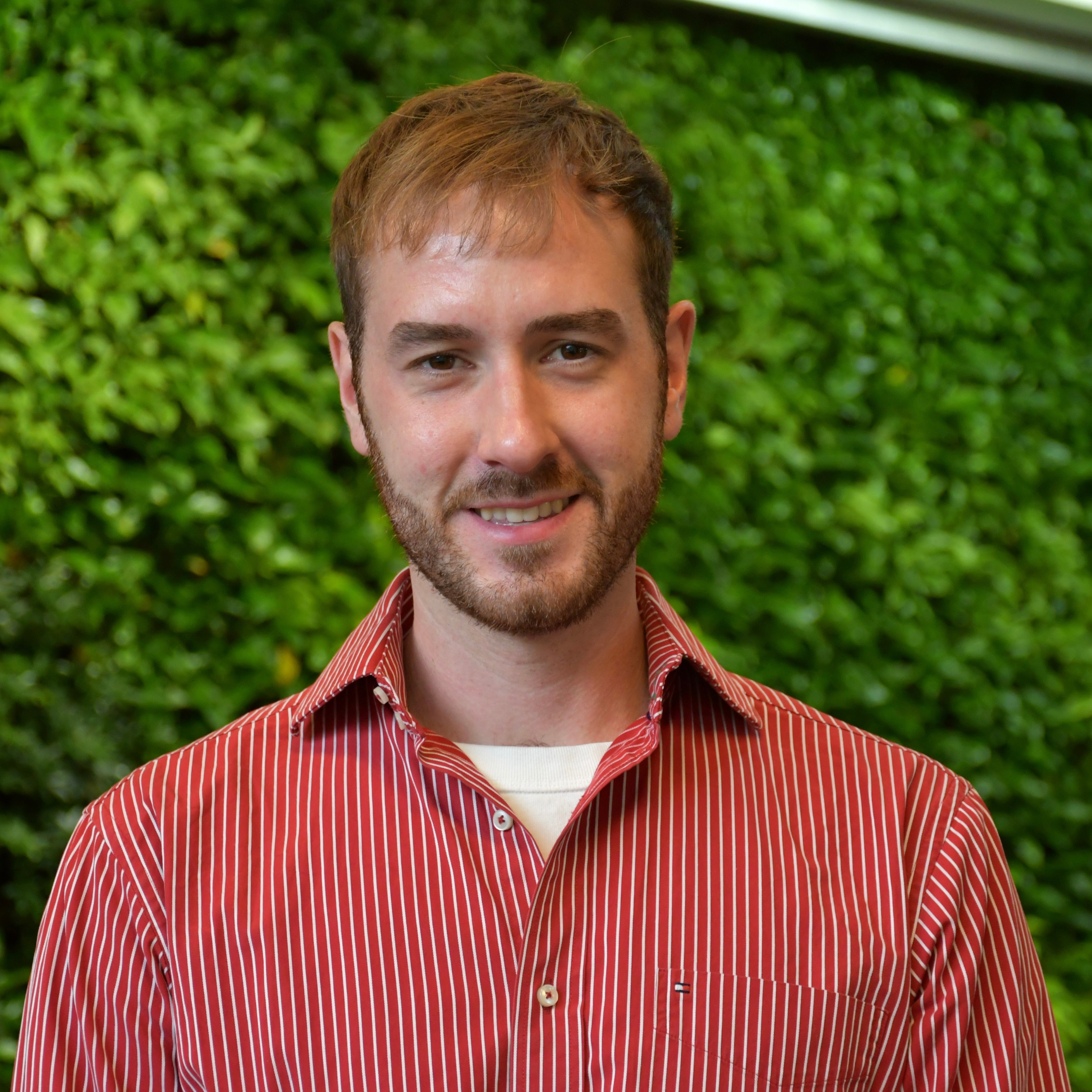 Head and shoulder shot of person before green plant wall
