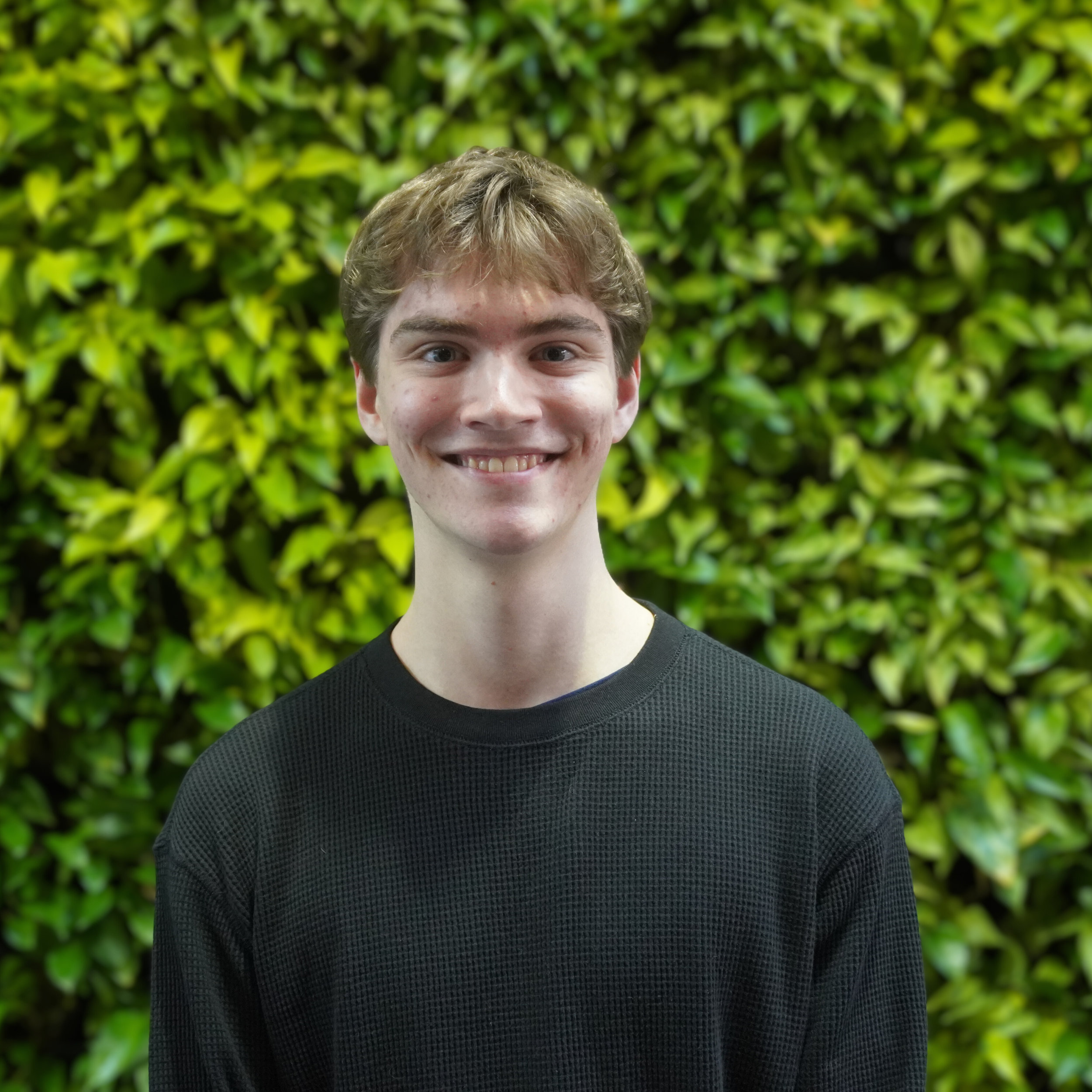 Head and shoulder shot of a person before a green plant wall