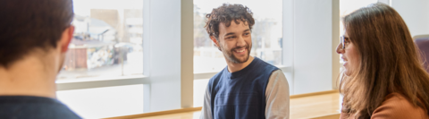 Two students chat by a window