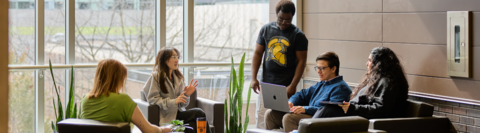 Five students gather and chat in a common area