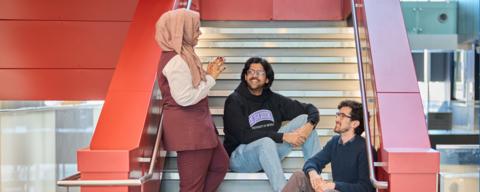 Engineering students chatting on the iconic red staircase in E7.