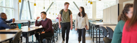 Two students walk and chat in a classroom