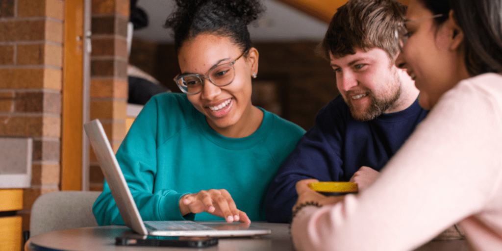 Three students work on a laptop