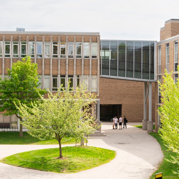 Group of students by the Engineering 2 (E2) building underneath an overpass, shot from a high angle.