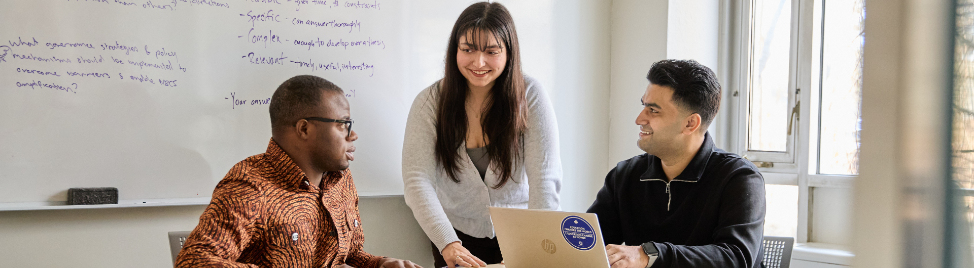 Three students converse around a table