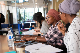 Students work together at a table with laptops
