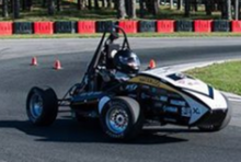 student-designed race car going around race track