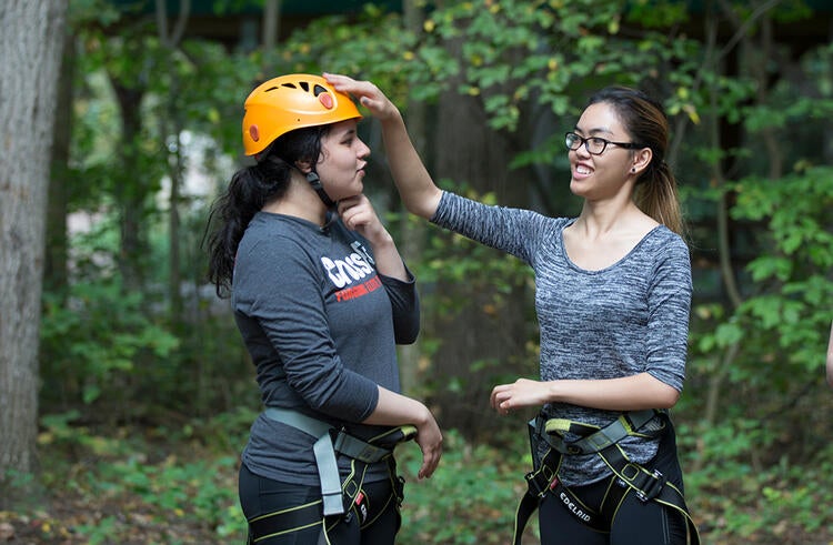 A Recreation student adjusting her classmate's helmet on a first-year class retreat.