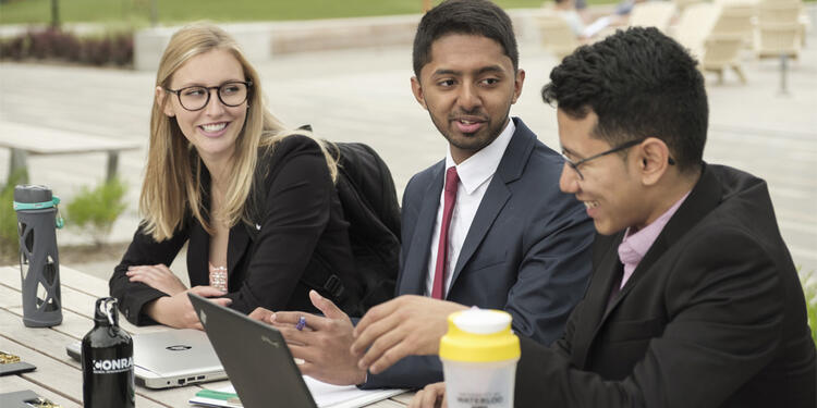 Students in a co-op program dressed in business attire at a table outside. 