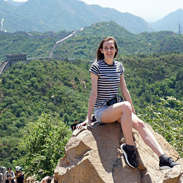 Jessica sitting on a rock with the Great Wall of China behind her