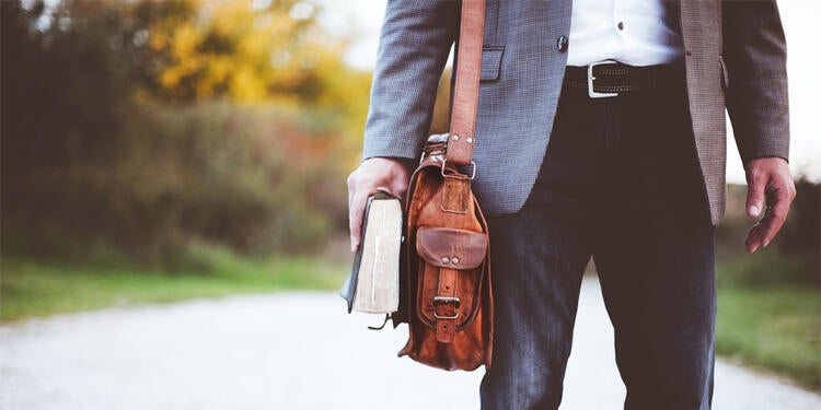 A person holding a book and briefcase.