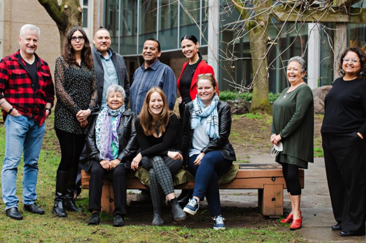 Indigenous professors and staff standing and sitting outdoors